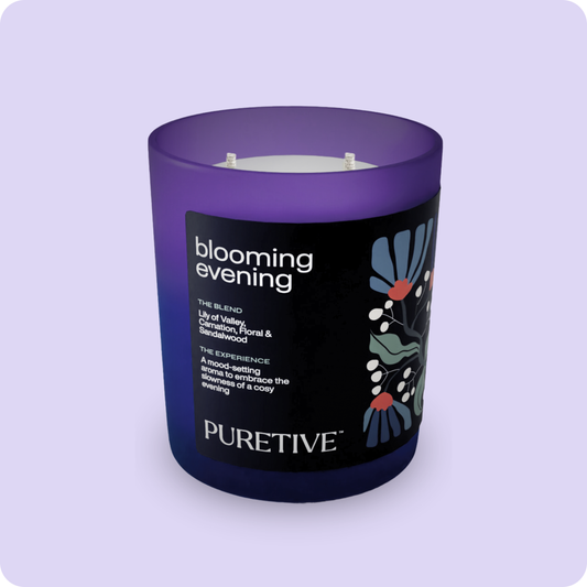 A purple scented candle with two wicks, labeled "blooming evening" by "PURETIVE," against a lilac background.