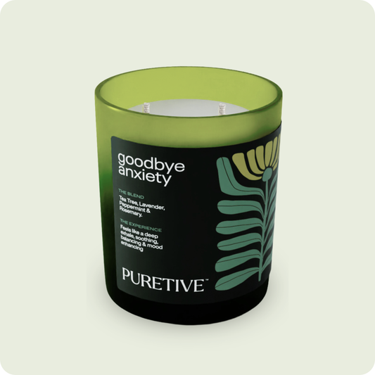 Scented candle labeled "goodbye anxiety" from PURETIVE with a green and black design.