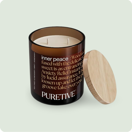 A scented candle with two wicks in a brown jar and a wooden lid beside it, labeled "PURETIVE".